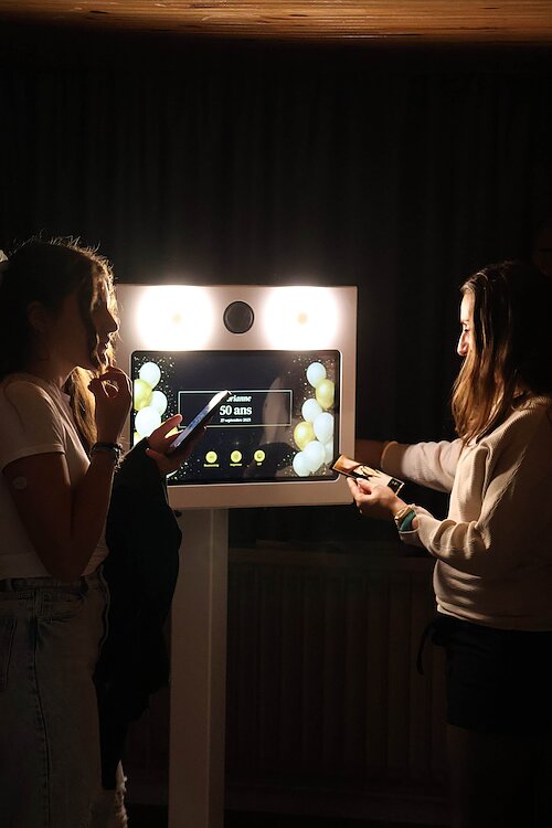 Adolescentes devant la borne photo partageant leurs photos sur les réseaux
