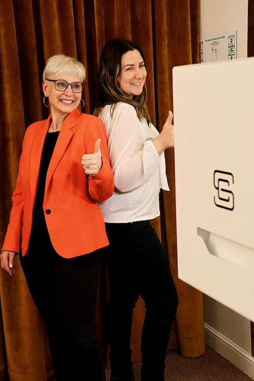 Deux participantes souriantes faisant un pouce levé devant la borne photobooth - afterwork Groupe SME