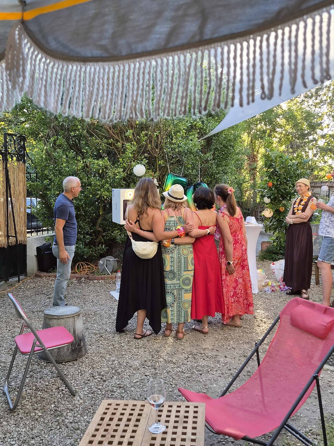 Invitées prenant la pose devant le photobooth installé dans le jardin pour les 50 ans d’Anne