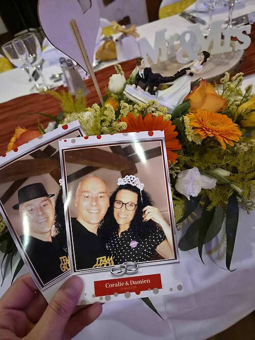 Deux tirages personnalisés du photobooth devant le bouquet et les statuettes des mariés