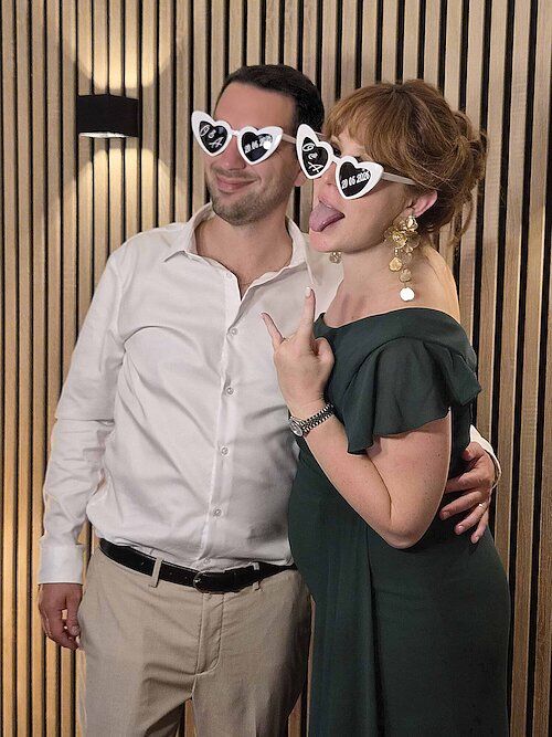 La témoin des mariés pose avec son mari devant le photobooth pendant la réception au Domaine de Crécy